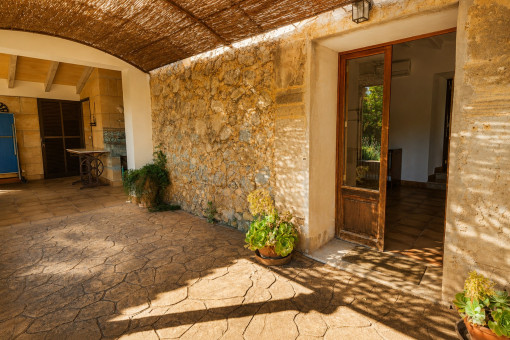 Ueberdachte Patio-Terrasse mit Natursteinwand und Pflanzen