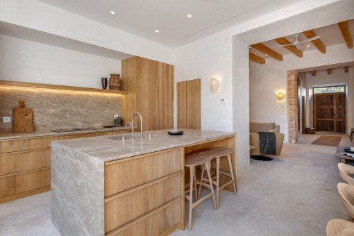 Offene Küche mit Natursteininsel und Blick ins Wohnzimmer 