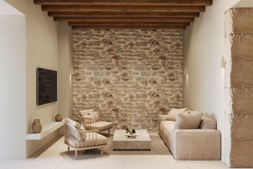 Wohnzimmer mit Steinwand und Holzbalkendecke – traditionelles Mallorquinisches Flair modern interpretiert