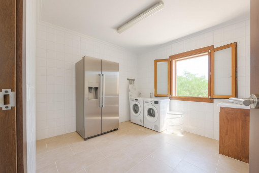 Hauswirtschaftsraum mit Waschmaschine, Trockner und großem Kühl-Gefrierschrank – viel Platz und Licht.