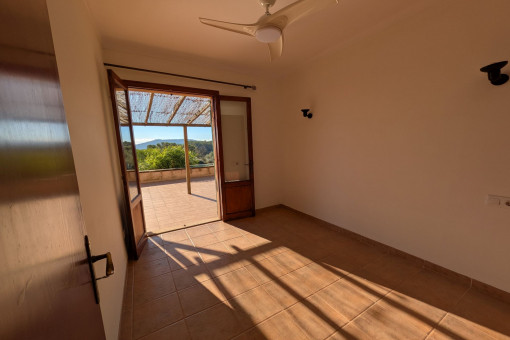 Helles Schlafzimmer mit Zugang zur Terrasse und Blick in die Natur