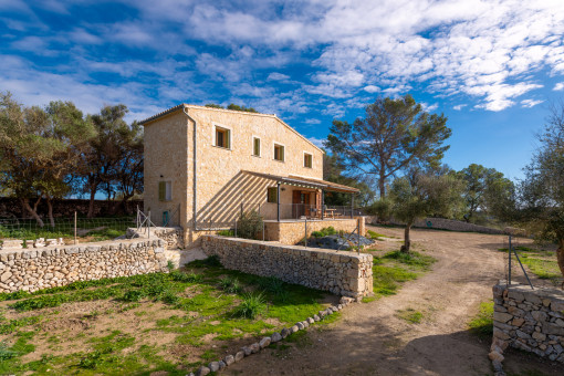 Außenansicht der Finca mit Natursteinfassade, überdachter Terrasse und mediterraner Umgebung