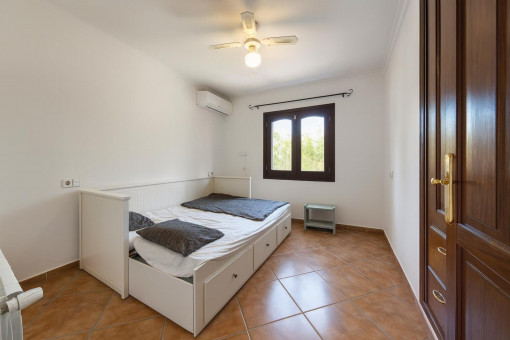 Schlichtes Schlafzimmer mit Fenster und Ventilator