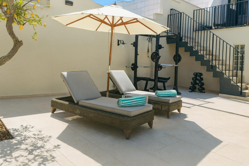 Sonnige Terrasse mit Liegen und Fitnessbereich