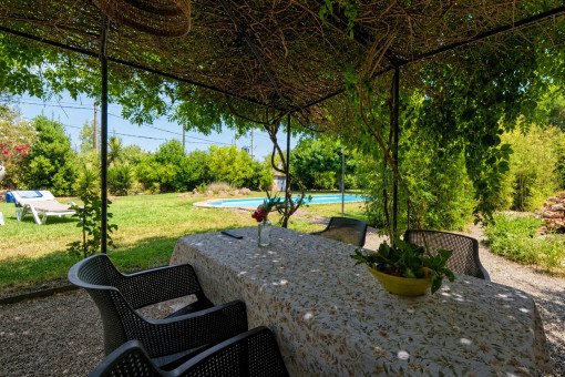 Überdachter Essplatz mit Blick auf Pool und Garten