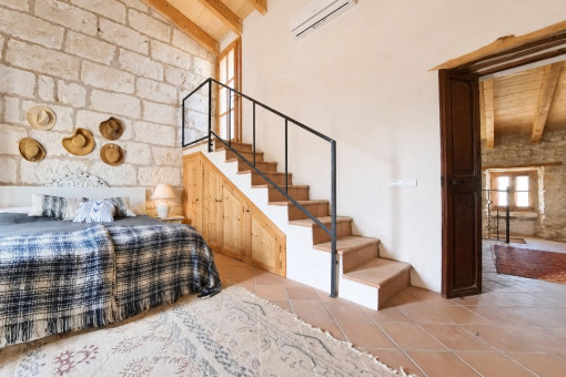 Gemütliches Schlafzimmer mit Steinwand und Treppe